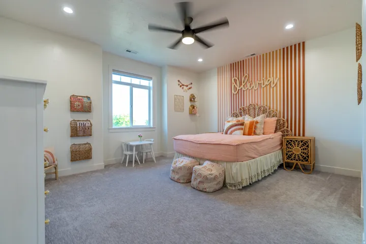 Bedroom featuring a textured accent wall, recessed lighting, ceiling fan, carpet flooring, and a double-pane window