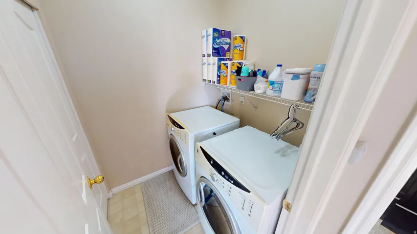 Dedicated laundry area featuring a front-load washer and dryer, tile flooring, and integrated wire shelving