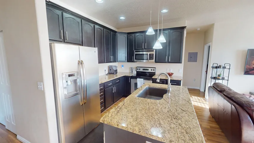 Kitchen featuring dark cabinetry with brushed nickel hardware, granite countertops, and stainless steel appliances