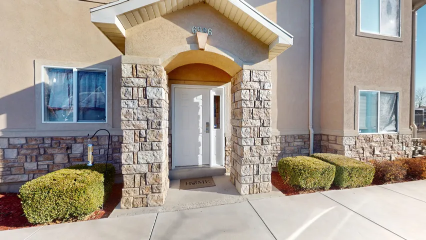 Inviting stucco exterior featuring a stone facade and an arched entry