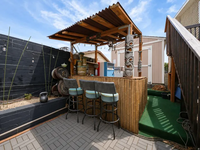Outdoor bar structure featuring a corrugated roof and bamboo-wrapped counter