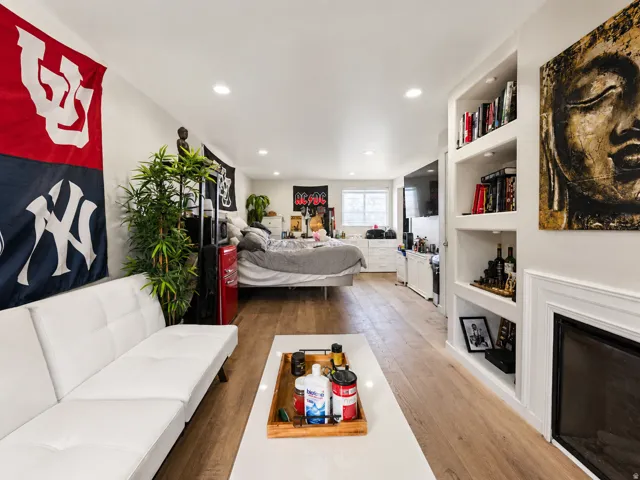Open-concept living space with light wood-finish flooring, recessed lighting, built-in shelving, and a decorative fireplace