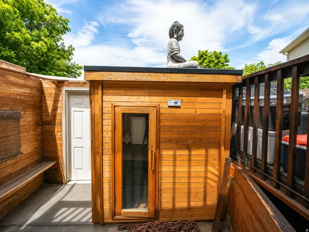 Freestanding wood-paneled sauna featuring a glass-paned door and exterior controls
