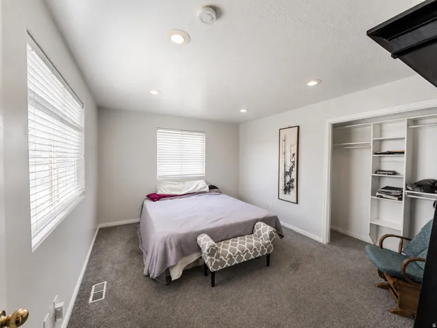 Bedroom with two windows featuring horizontal blinds, recessed lighting, and grey carpeting