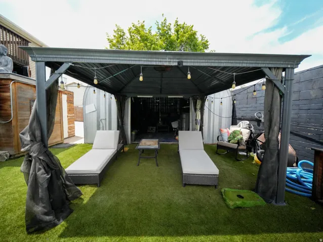 Outdoor entertaining area featuring a dark-toned metal gazebo with string lighting