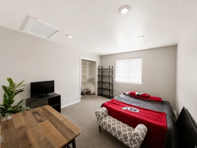 Carpeted room featuring a window with blinds, recessed lighting, and a closet with built-in shelving