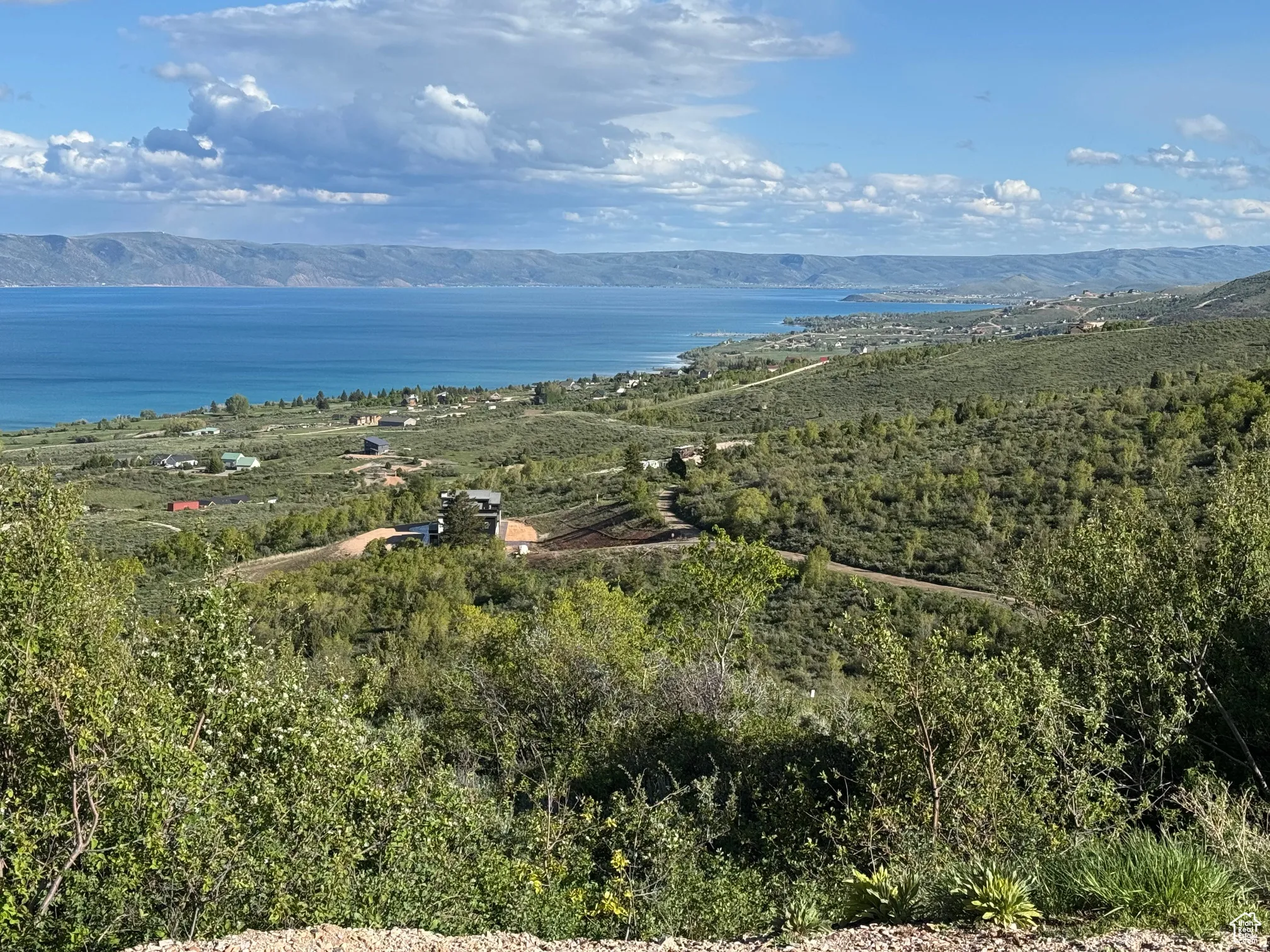 Expansive landscape featuring a large body of water, distant mountains, and varied topography
