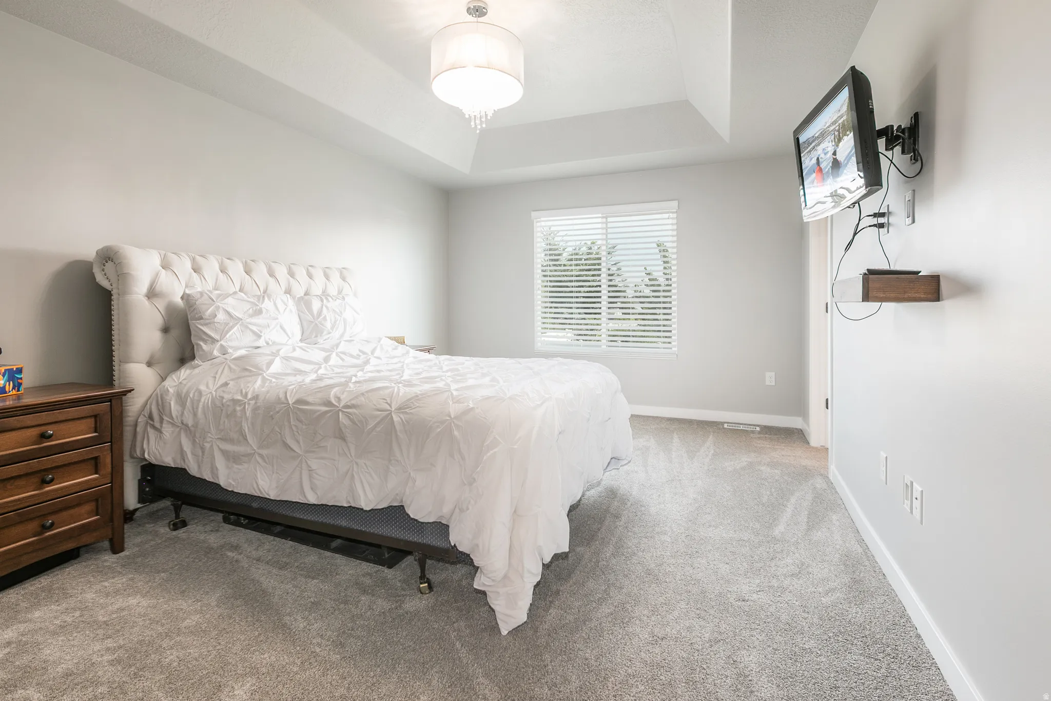 Carpeted room with a tray ceiling and a chandelier light fixture
