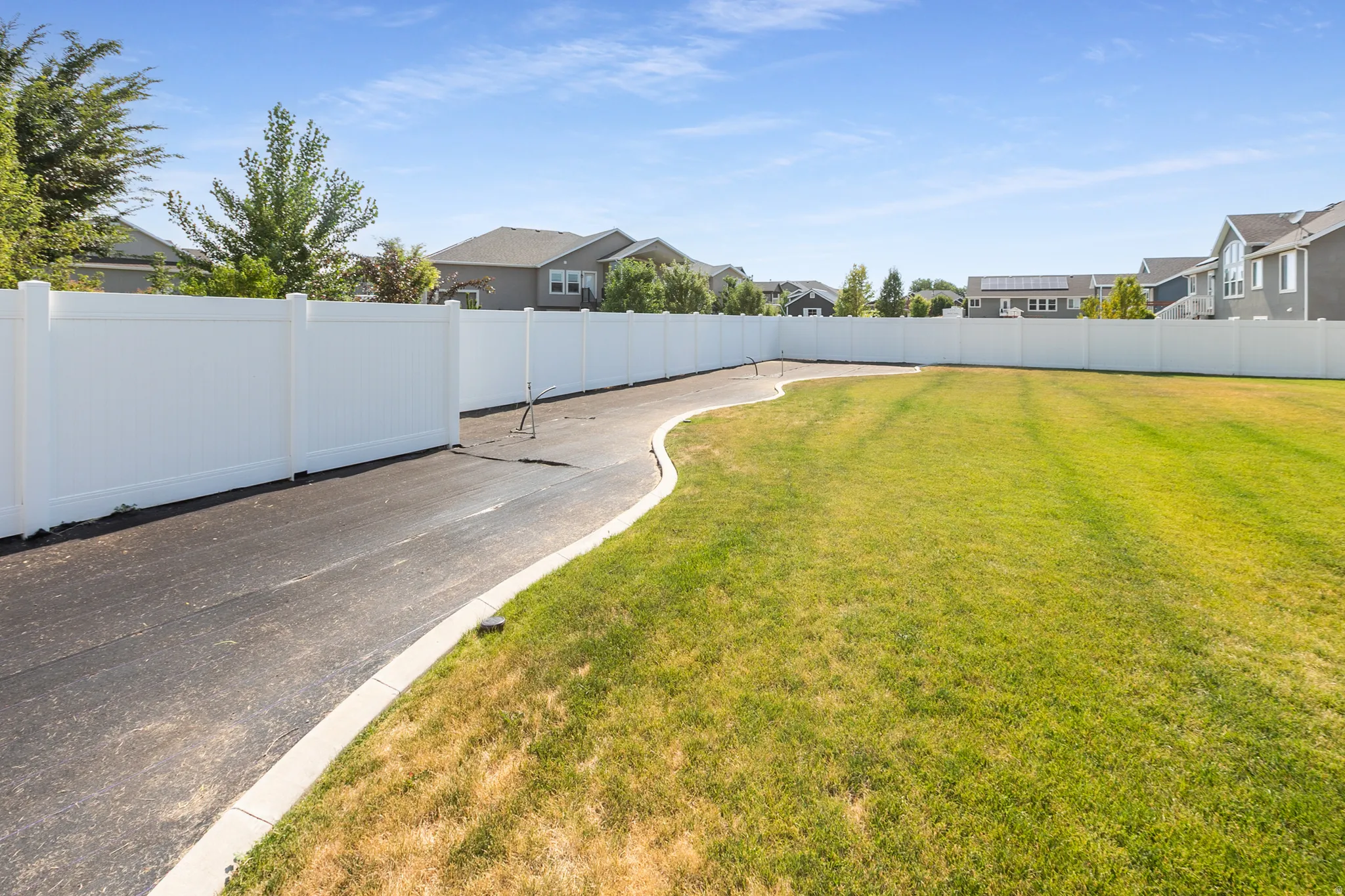 Expansive outdoor space featuring a large lawn area and a paved path