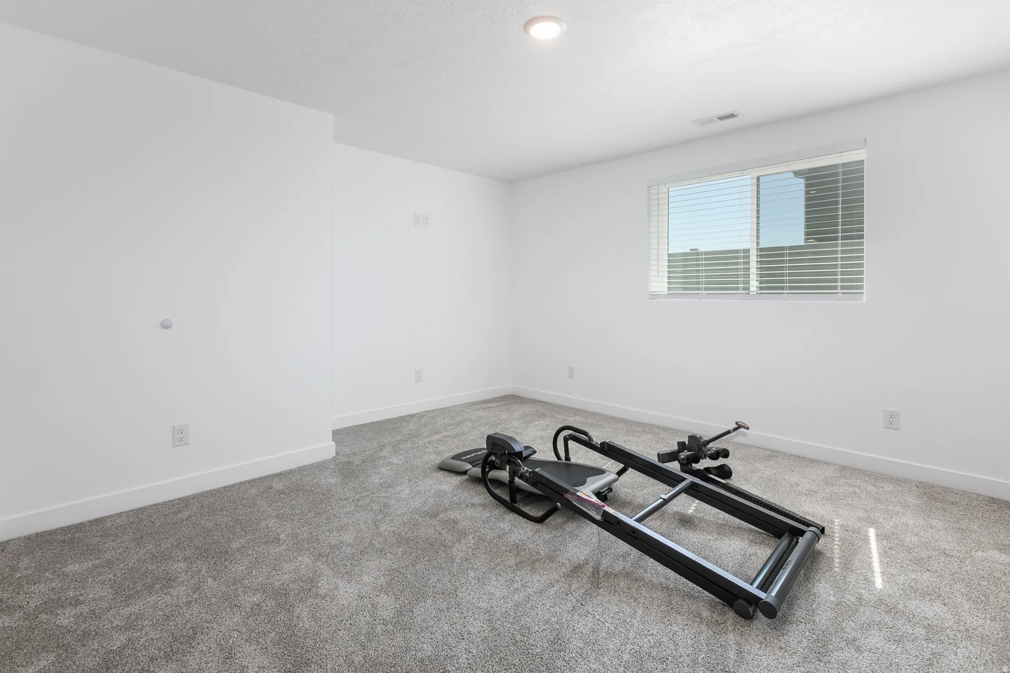 Carpeted room featuring a white window with horizontal blinds, recessed ceiling lighting, white baseboards, and neutral wall tones