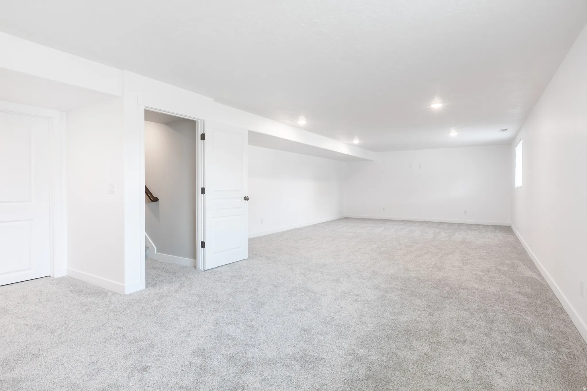 Spacious room with light gray carpeting and white walls