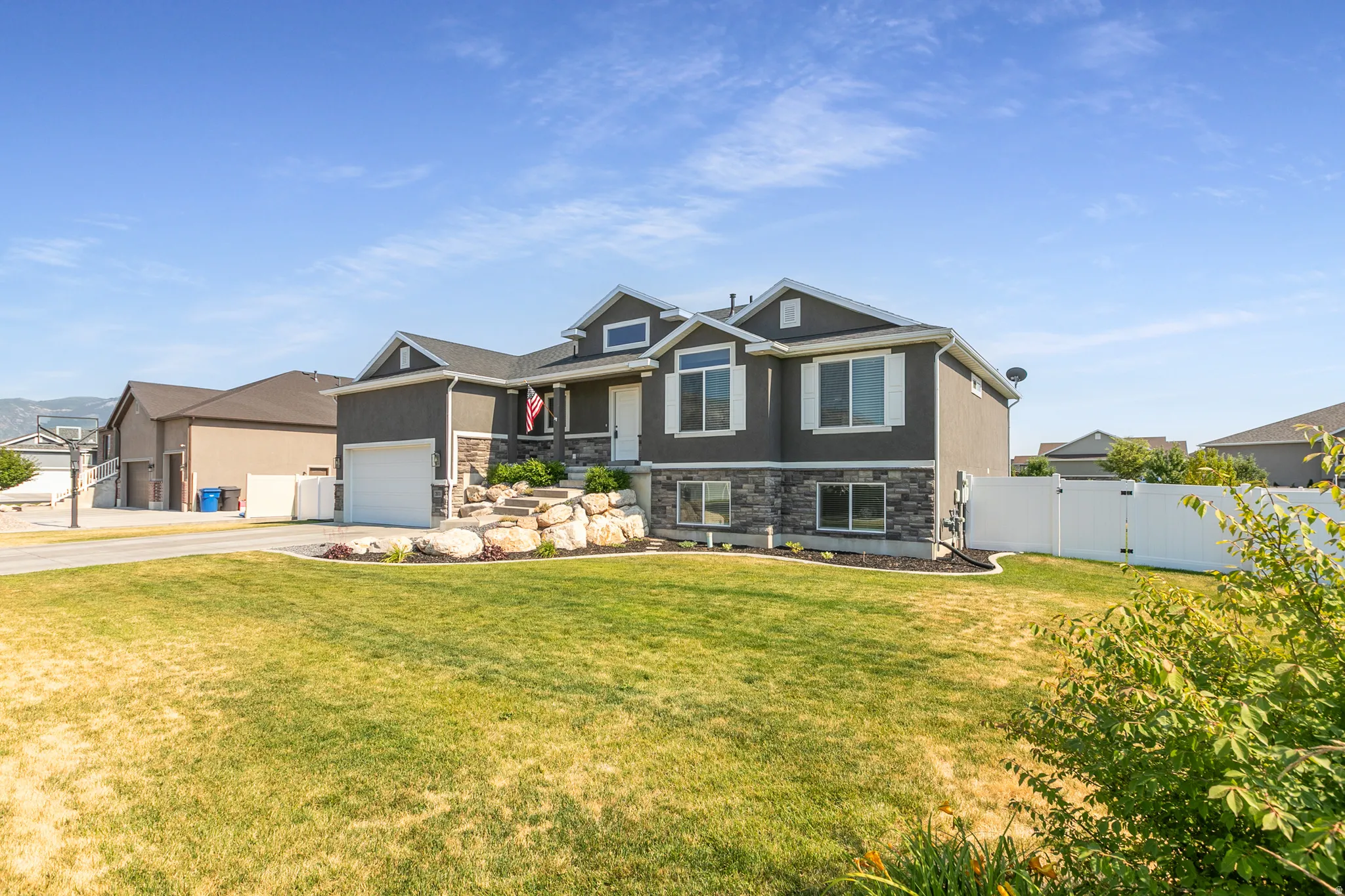 Two-story residence featuring a dark gray siding exterior and stone veneer accents