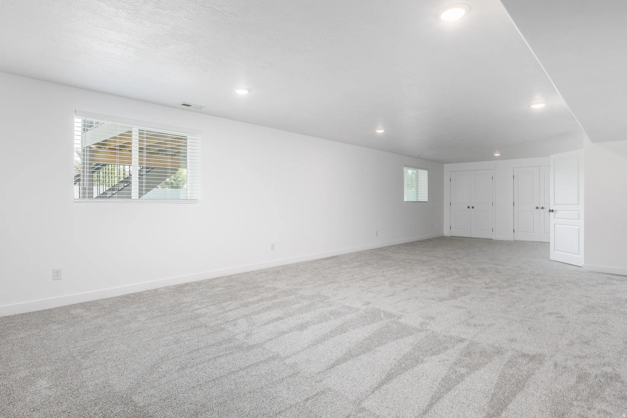 Expansive room featuring plush patterned carpeting and bright white walls