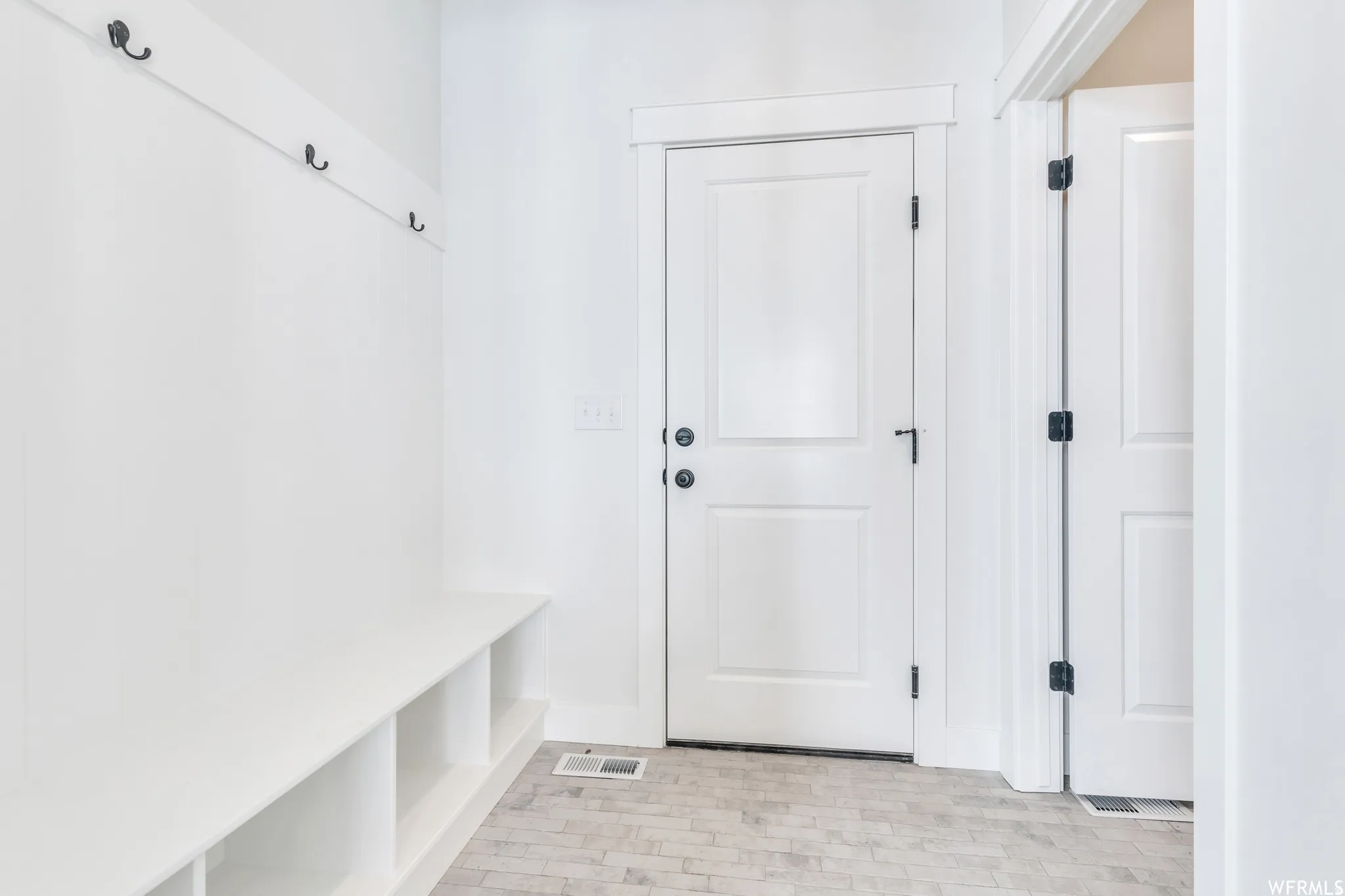 Entryway featuring a built-in bench with integrated cubby storage, wall-mounted coat hooks, and light-toned tile flooring