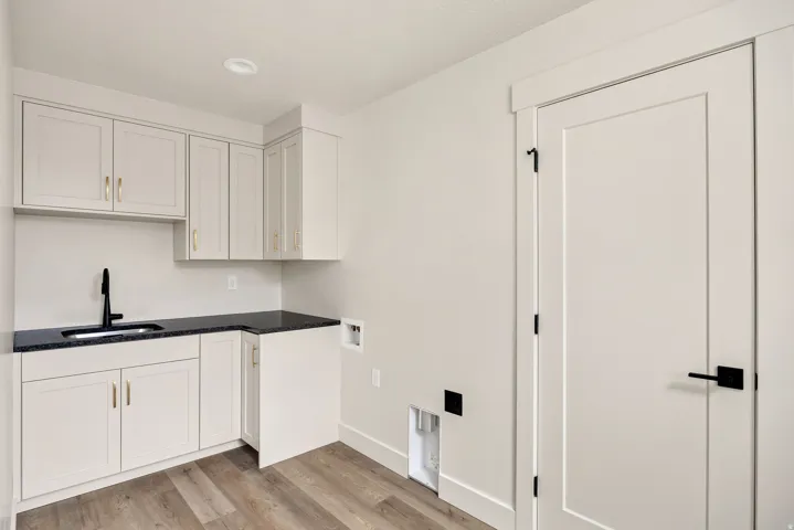 White cabinetry with gold-tone hardware, dark countertop, and a matte black faucet