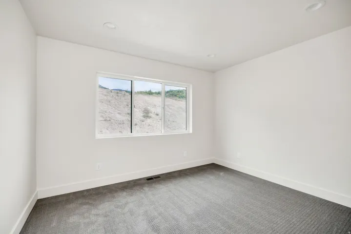 Neutral wall finish, recessed ceiling lighting, a large window, and gray carpeting