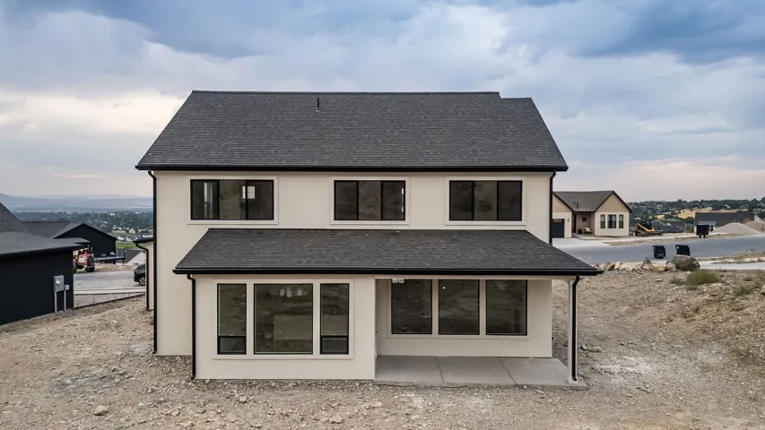 Two-story stucco exterior with a dark shingle roof and black-framed windows