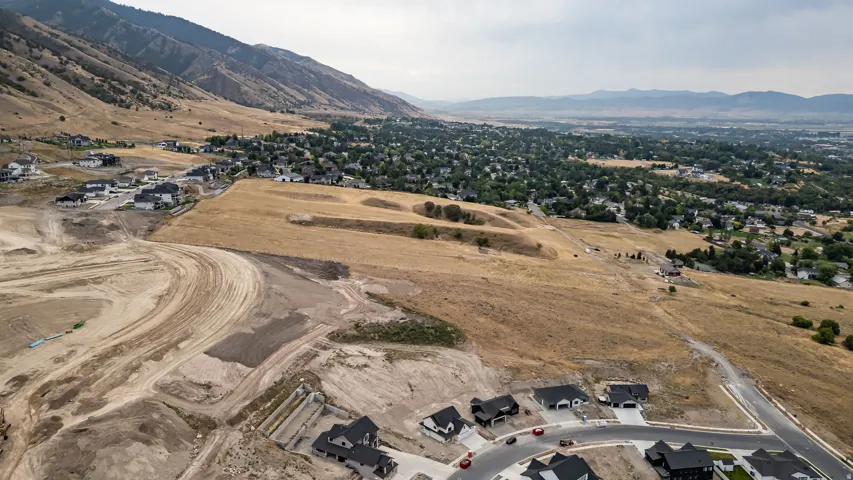 Expansive land with mountain backdrops, surrounding residential developments, and a paved road