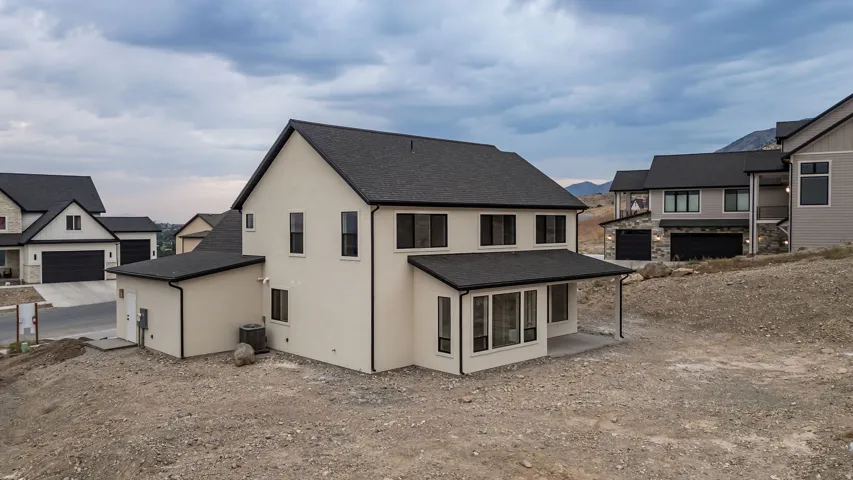Contemporary stucco exterior with a dark asphalt shingle roof, black-framed windows, and a covered patio area