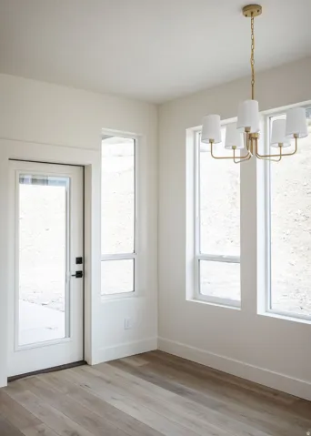 Wood-finish flooring, white walls, and a gold-tone chandelier with white fabric shades