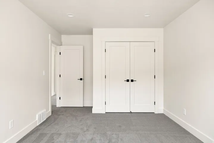 Neutral wall color, recessed lighting, white trim, paneled doors, and carpeted flooring