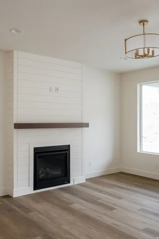 Shiplap accent wall with built-in fireplace, recessed lighting, wood-finish flooring, and a contemporary drum chandelier