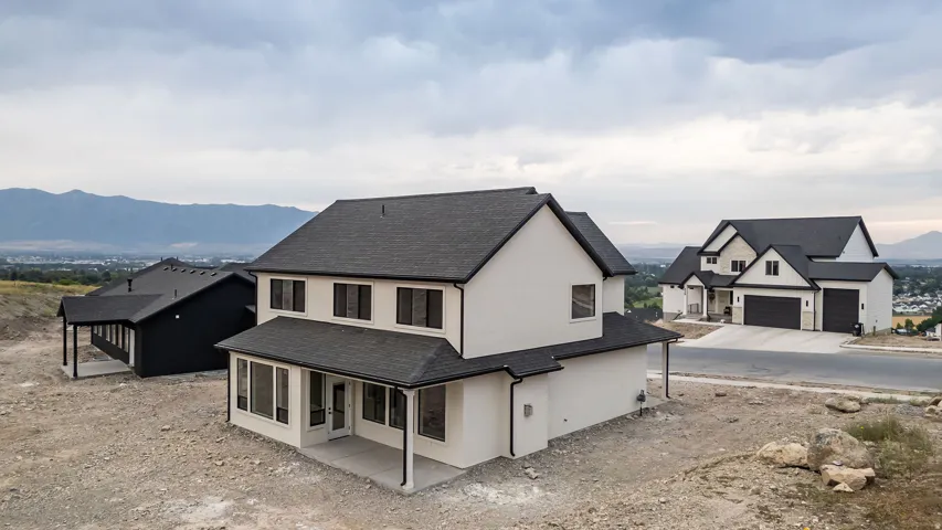 Contemporary two-story exterior with dark roof, light-colored siding, and a covered patio