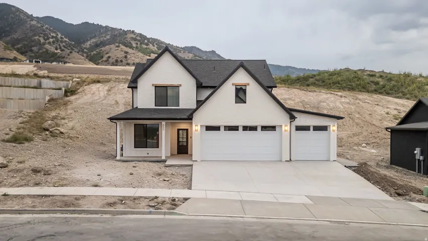 Modern farmhouse exterior with a dark shingle roof, white brick facade, and a two-car garage