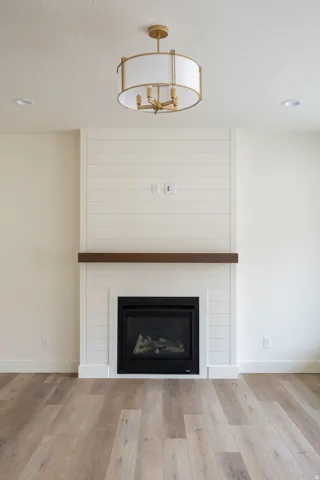 Fireplace with a shiplap surround, wood mantel, and gas insert