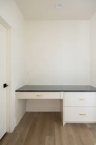 Built-in desk featuring a dark countertop and light-colored cabinetry with gold-tone hardware