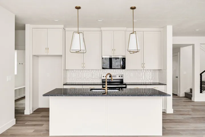Kitchen featuring a central island, dark countertops, white cabinetry, and a textured tile backsplash