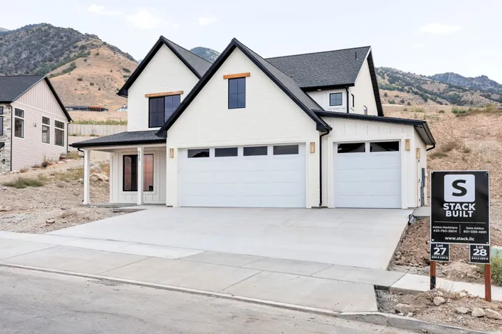 White brick exterior with black trim, a gabled roofline, a two-car garage, and a covered entry