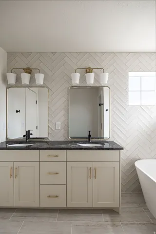 Dual vanity with light-toned cabinetry, dark countertops, and undermount sinks