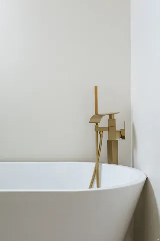 Freestanding soaking tub with a contemporary matte gold floor-mounted tub filler