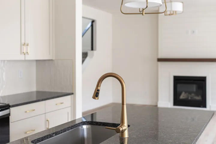 Kitchen island with a built-in sink, gold-finish faucet, and dark stone countertop