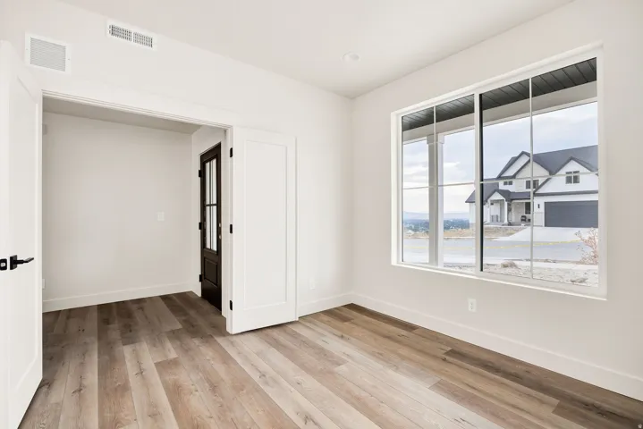 White interior walls, wood-finish flooring, recessed lighting, and a dark-frame glass-paned door