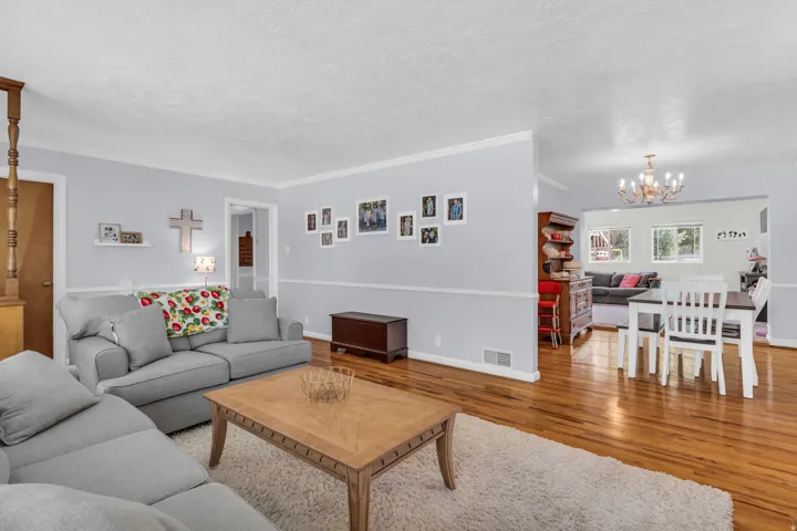 Open-concept living area featuring wood-finish flooring, a neutral color palette, white crown molding, and recessed lighting