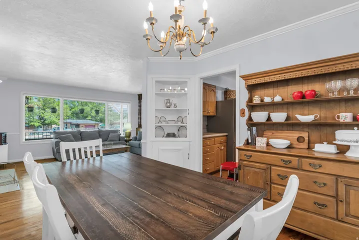 Spacious dining area featuring wood-finish flooring, an overhead chandelier, and crown molding