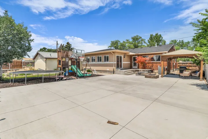 Expansive concrete patio area featuring a wooden pergola and a raised concrete patio