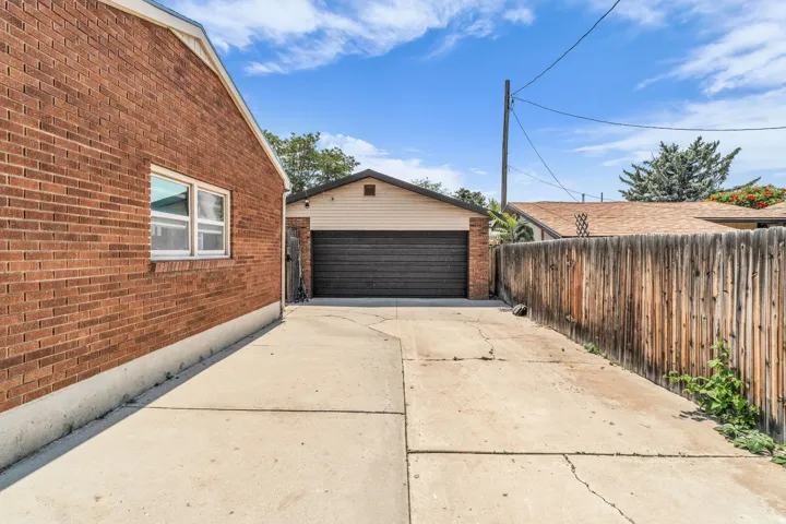Concrete driveway extending to a detached garage with a dark sectional garage door
