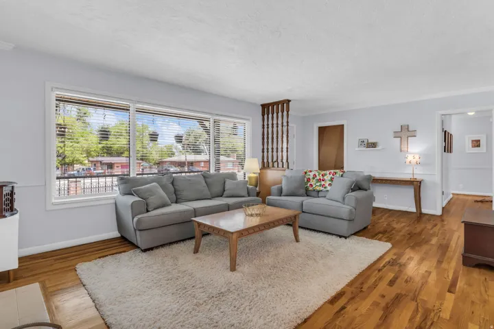 Living area featuring wood-finish flooring and a large window with horizontal blinds