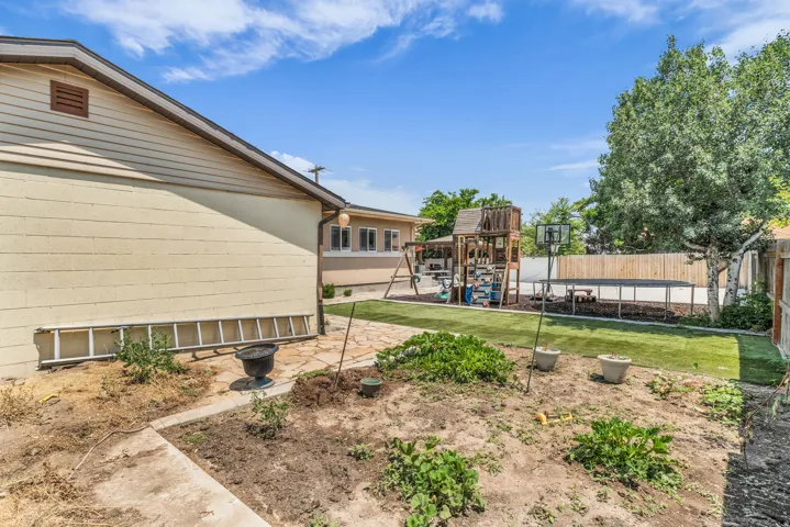 Expansive backyard area featuring a combination of natural ground cover, paver stone path, and artificial turf