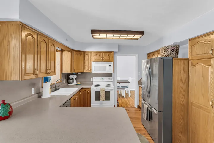 Kitchen featuring wood cabinetry, solid surface countertops, and white appliances