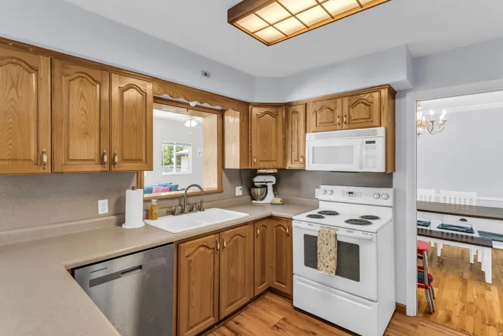 Kitchen featuring wood-finish cabinetry, a double basin sink, and a pass-through window
