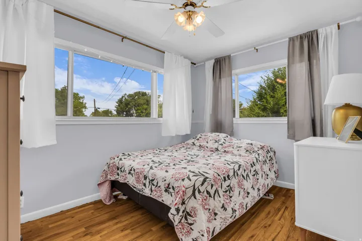 Room featuring wood-finish flooring, light grey walls, and a ceiling fan with integrated lighting