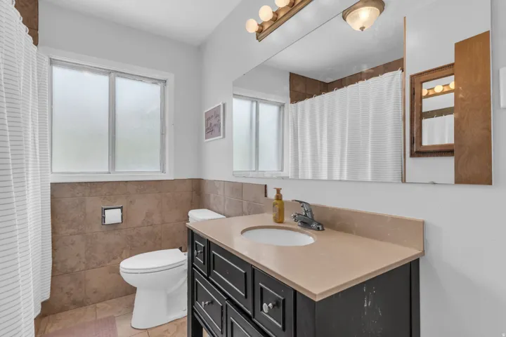 Bathroom vanity featuring a light-toned countertop with an integrated sink, polished chrome faucet, and dark wood-finish cabinetry