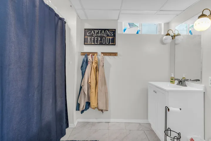 White vanity with a white countertop and chrome faucet, rectangular mirror, and dual light fixture