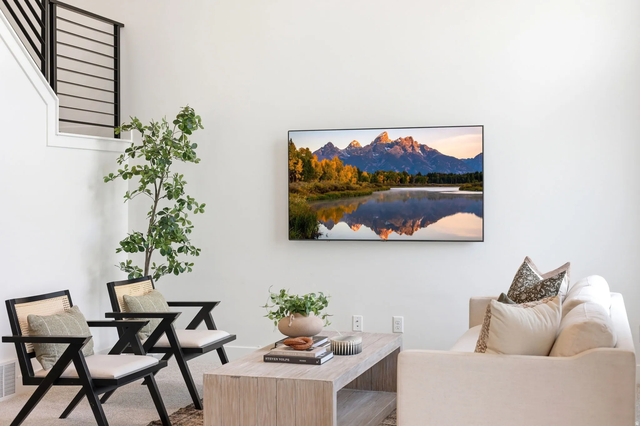 Living area featuring a wall-mounted television, light wood-finish coffee table, and white walls