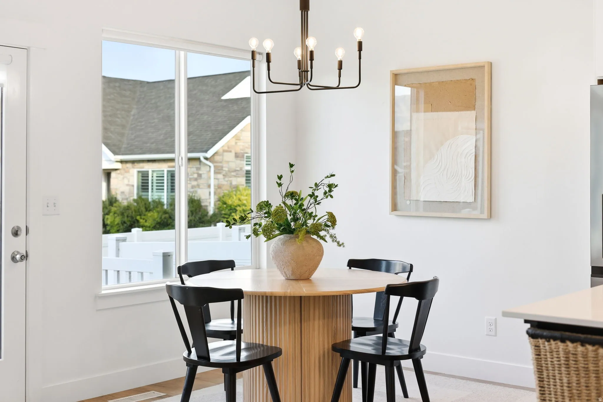 Dining area featuring a modern chandelier, large window, and wood-finish flooring