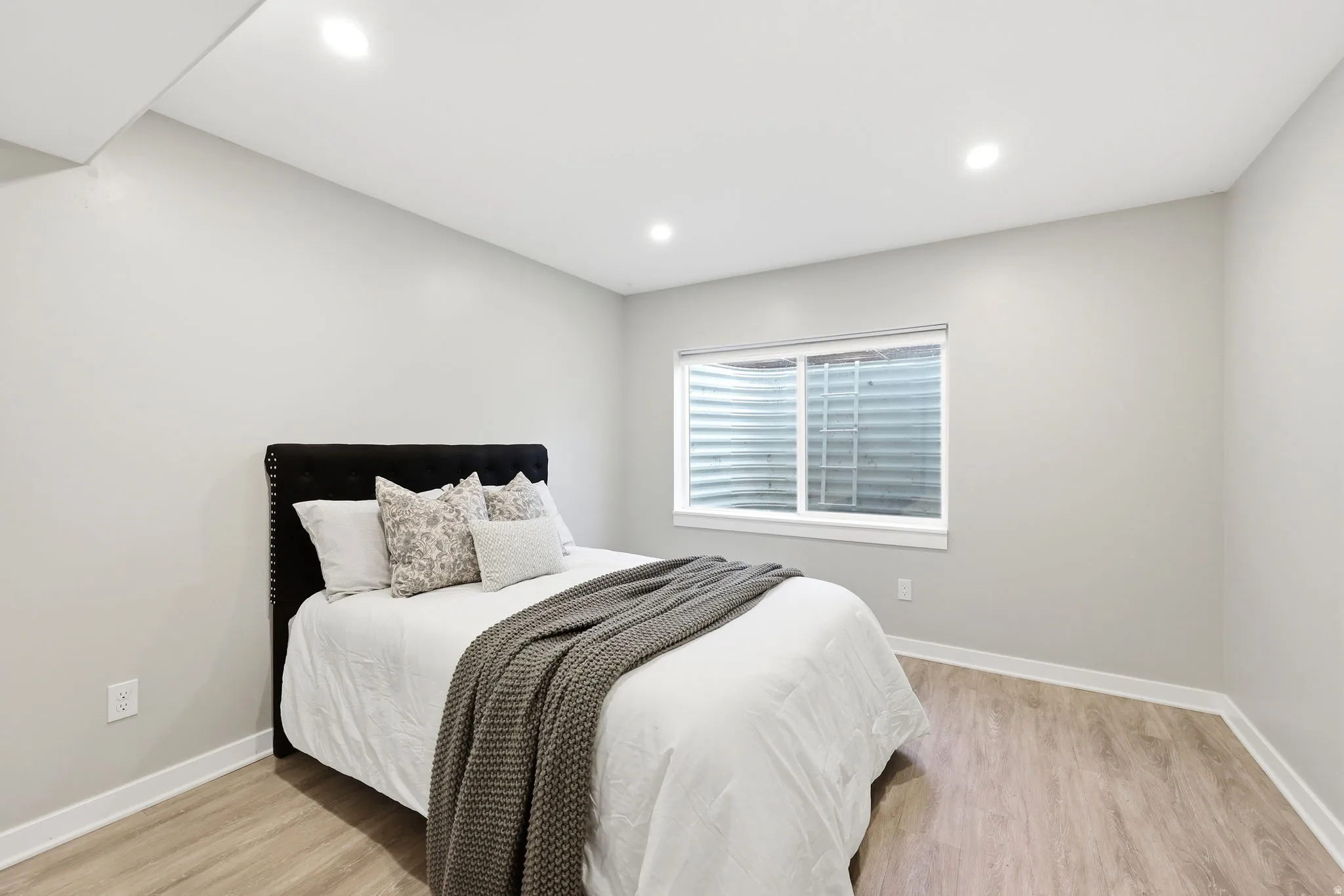 Bedroom featuring a single window, recessed lighting, light wood-finish flooring, and white trim
